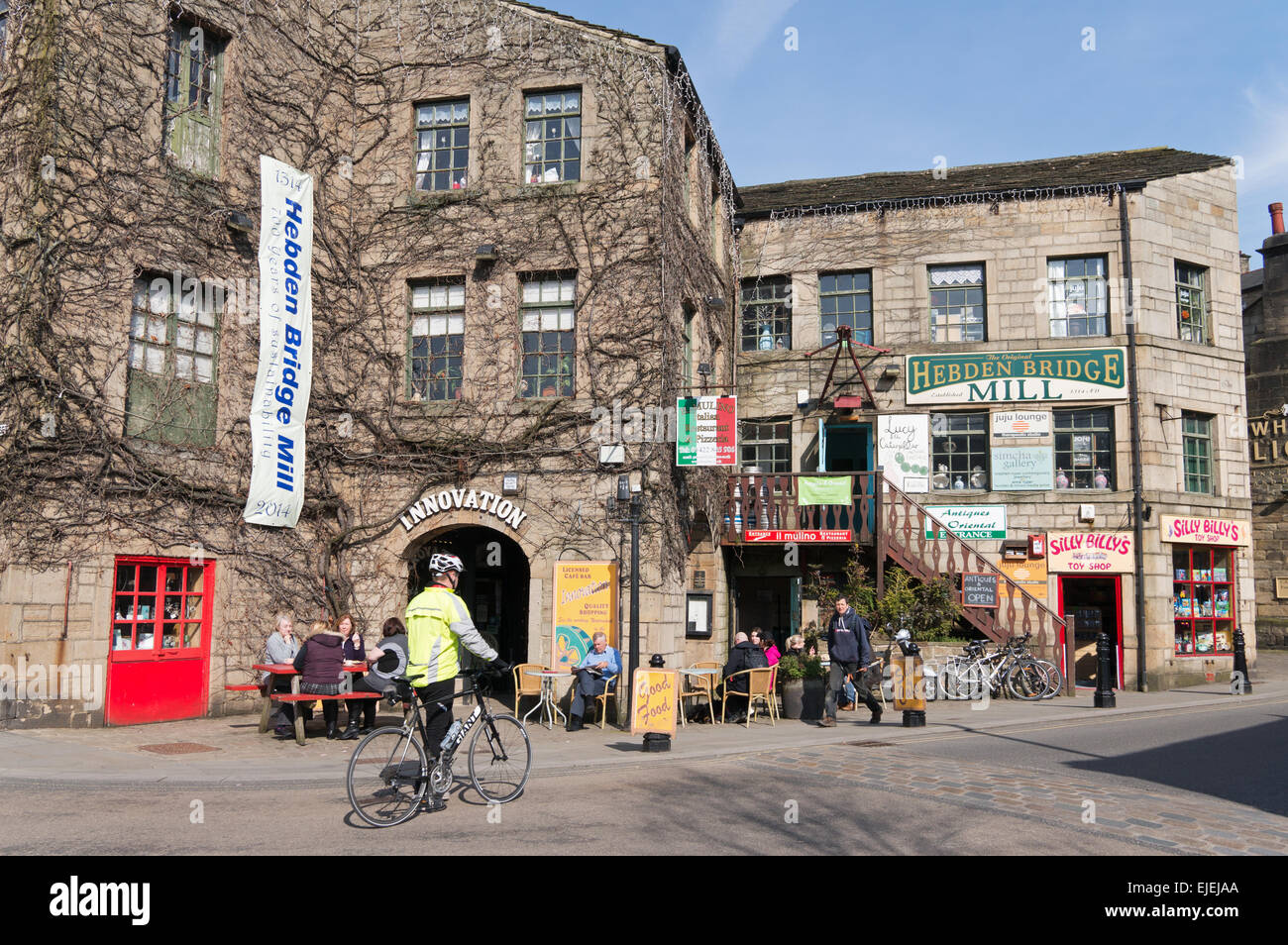 People sitting and cyclist walking town centre Hebden Bridge, West Yorkshire, England, UK Stock Photo