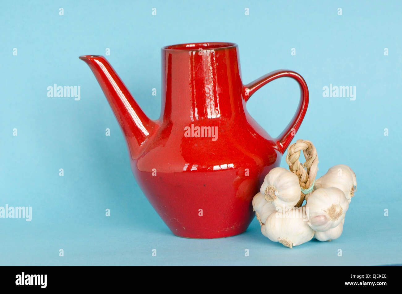 red ceramic jar pitcher and healthy garlic bulb bunch on azure