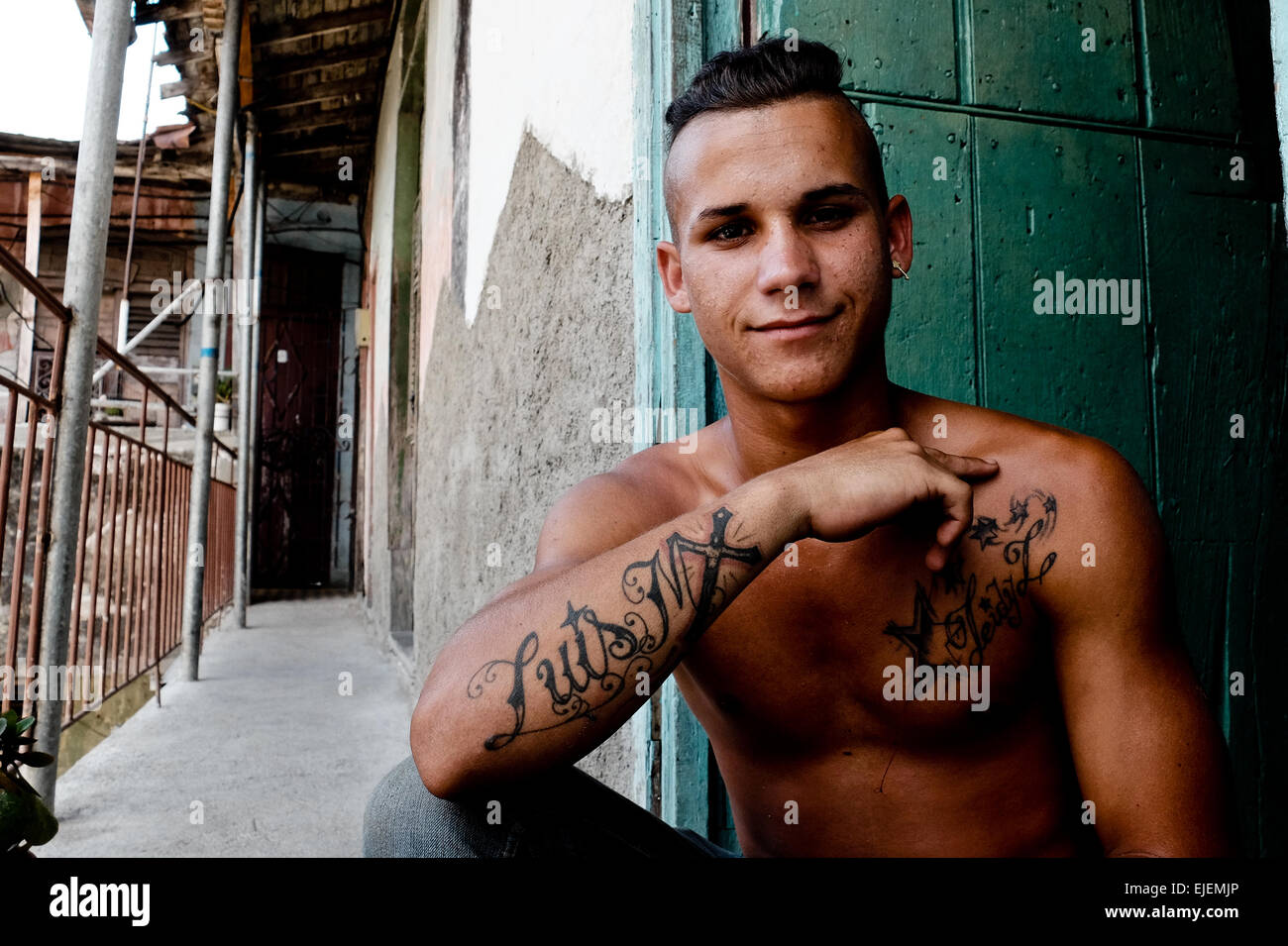 A young man shows off his tattoos in the hallway of his apartment ...