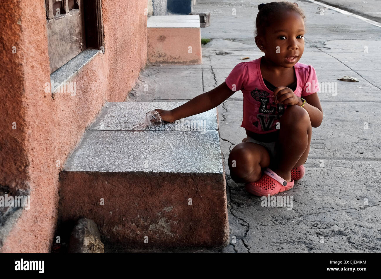 A young girl plays outside on the doorstep to her home in Cienfuegos.  Cubans spend much time at their doorways and many activities take place on  the doorstep and street, creating a