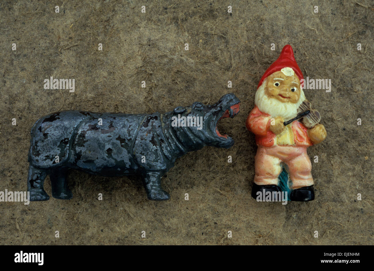 Toy models of hippopotamus with mouth wide open and gnome playing violin lying on antique card Stock Photo