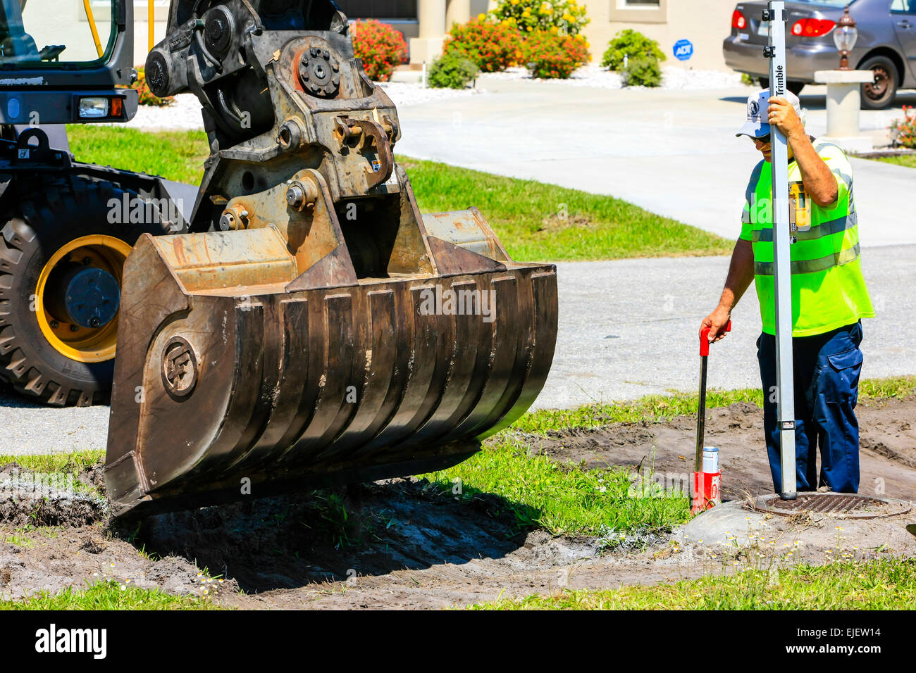 A backhoe removes sod from a residential street and regrades the