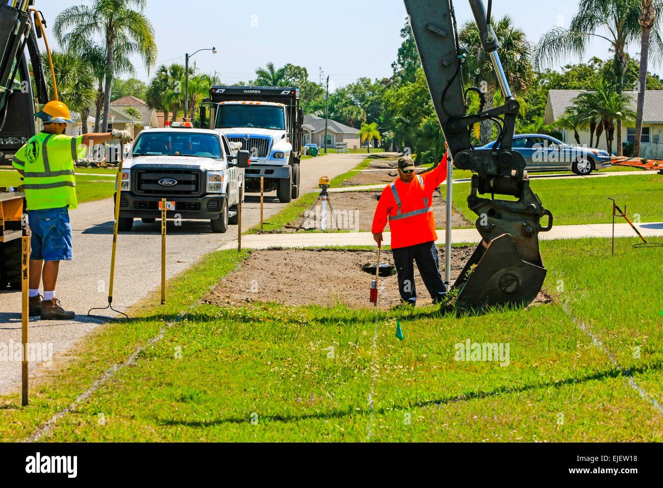 A backhoe removes sod from a residential street and regrades the