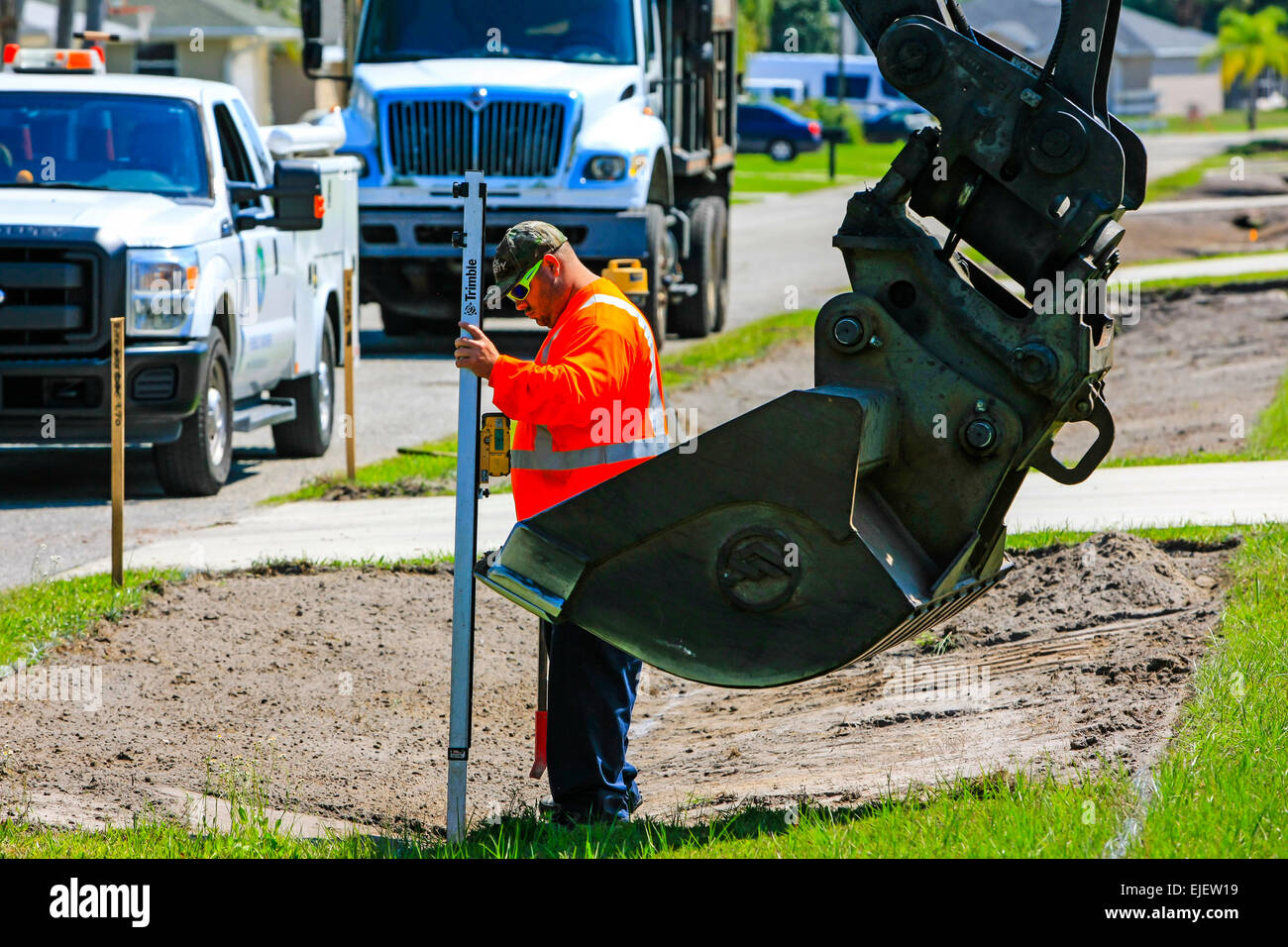 A backhoe removes sod from a residential street and regrades the