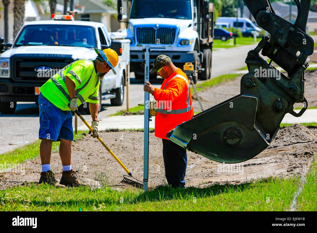 A backhoe removes sod from a residential street and regrades the