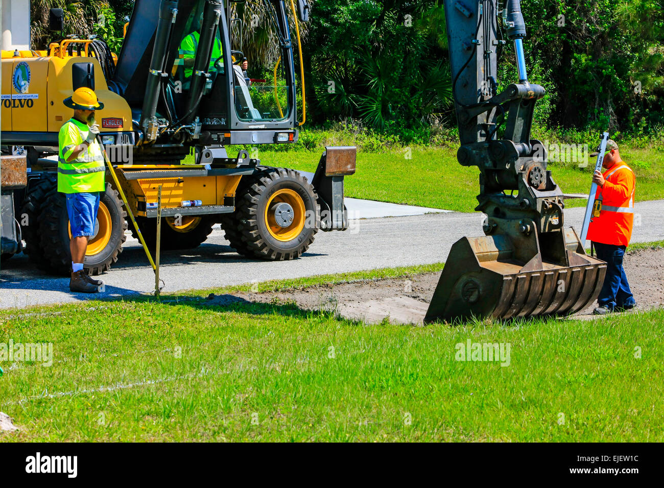 A backhoe removes sod from a residential street and regrades the