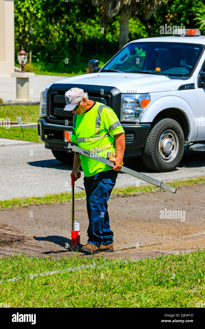 Highway maintenance worker using a digital depth guage as the backhoe