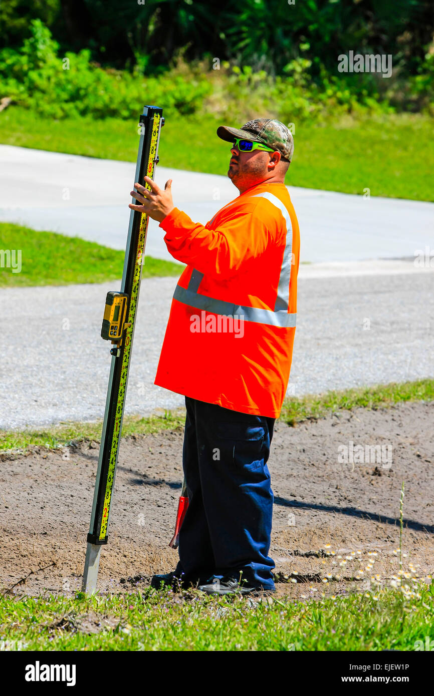 Highway maintenance worker using a digital depth guage as the backhoe