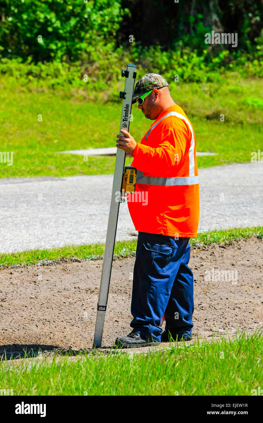highway maintenance worker using a digital depth guage as the backhoe EJEW1R