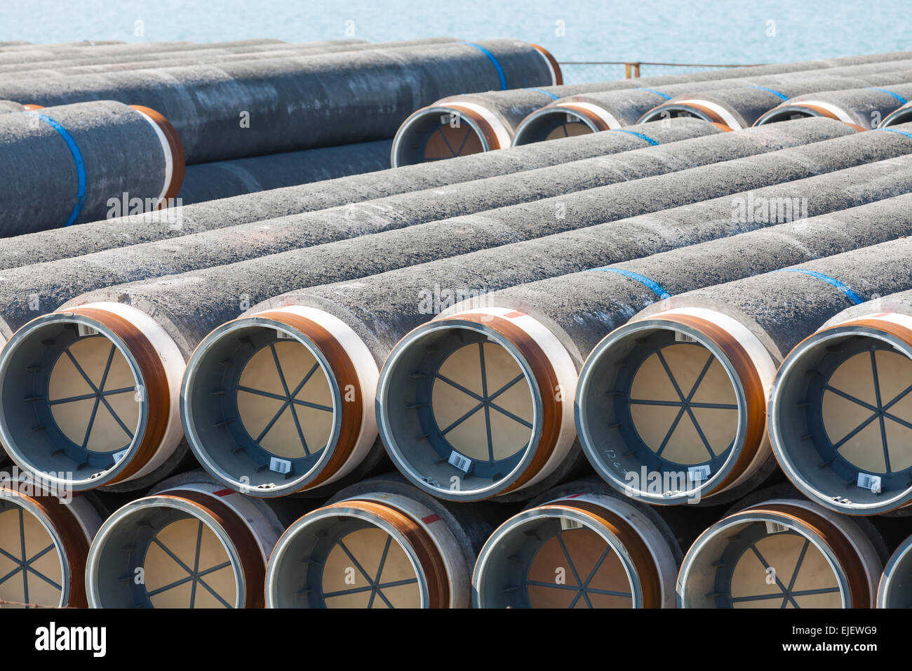Stacked pipeline tubes lay in outdoor storage area Stock Photo