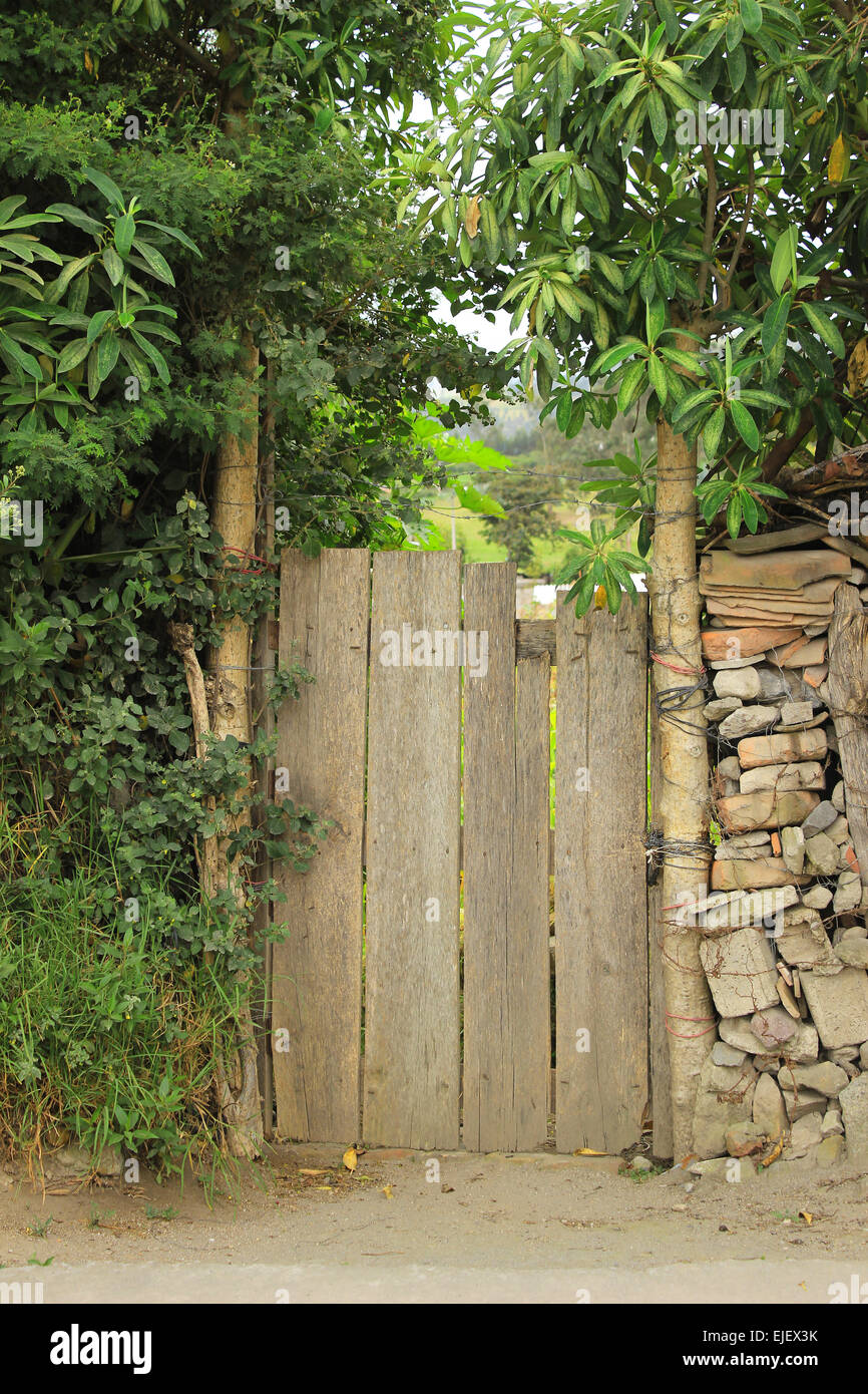 A wood gate in a wall of brick and stone with trees in Cotacachi, Ecuador Stock Photo