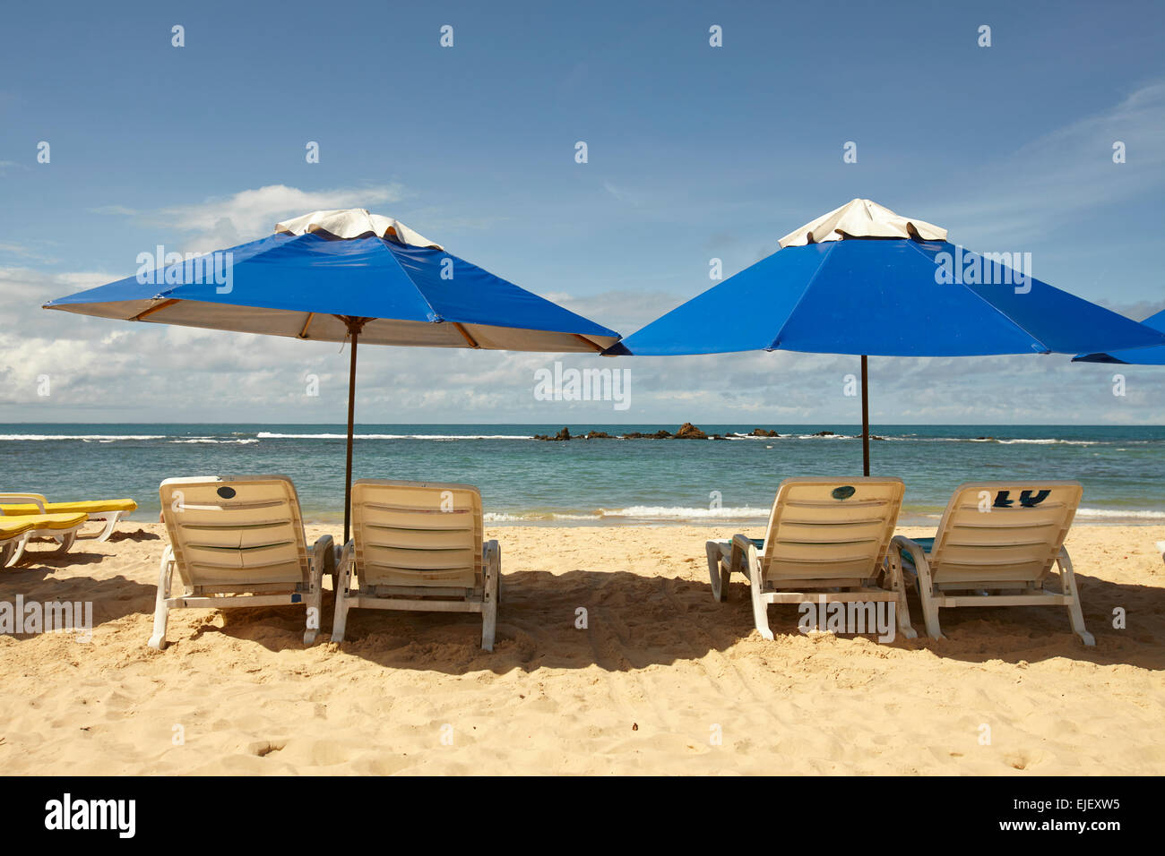 two blue beach umbrellas and sun loungers on a sunny beach in Brazil Bahia Morro Sao Paulo Stock Photo