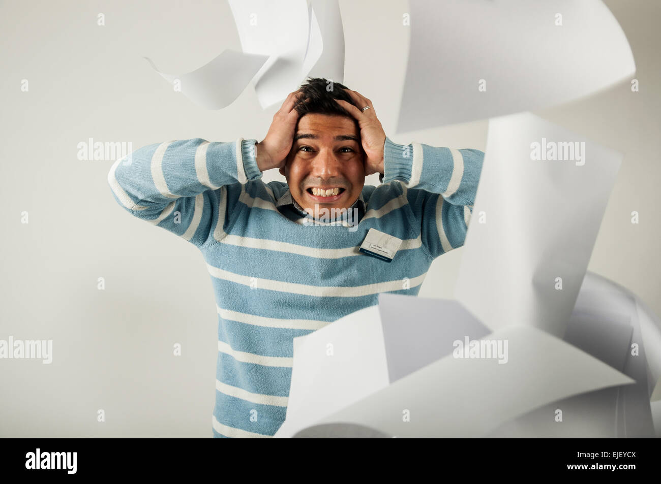 A stressed men around sheets of paper that fall everywhere. Un hombre estresado donde le caen las hojas de papel a su alrededor Stock Photo
