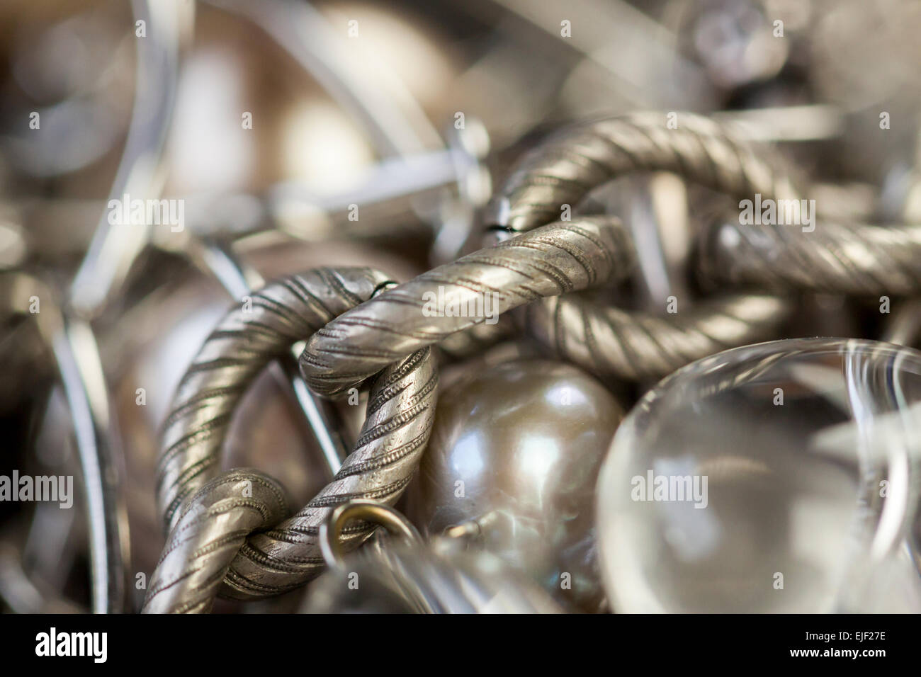 Assorted silver costume jewellery with a jumbled pile of chains with different shaped links, a clear crystal bead and a necklace Stock Photo