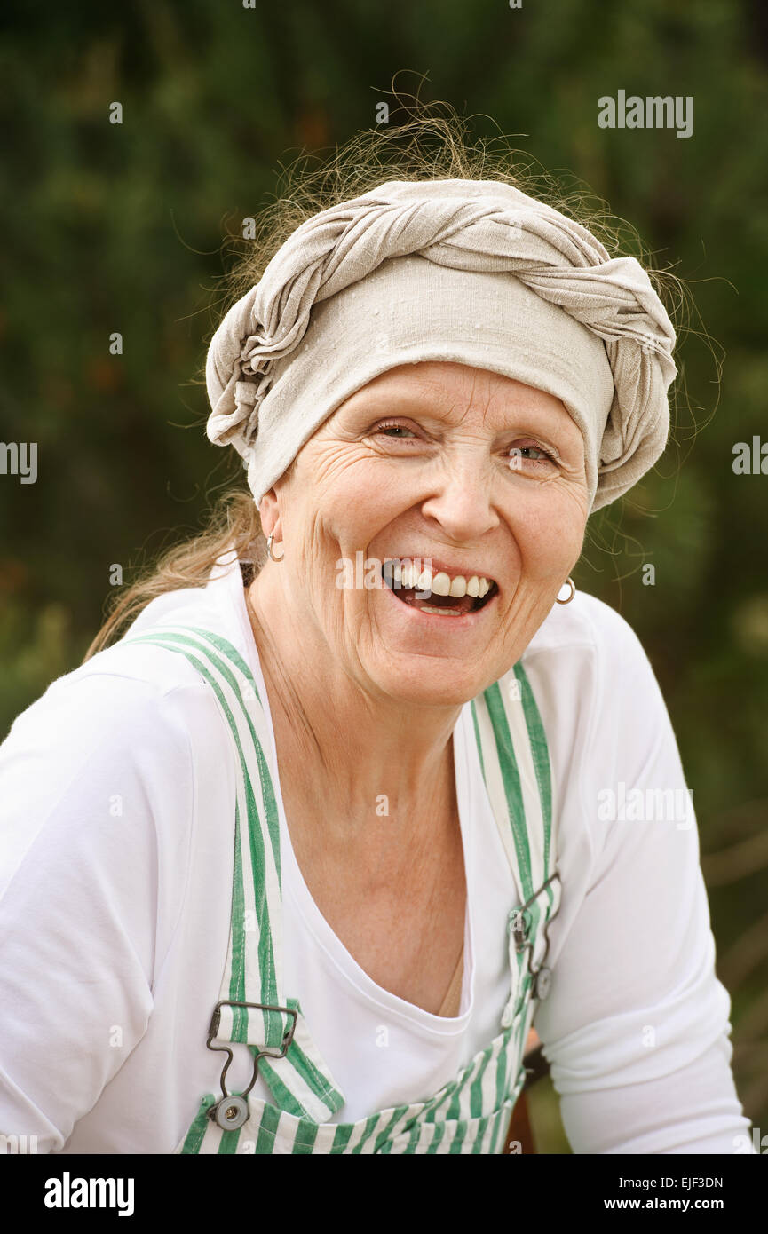 Senior woman looks at the camera and laughs. Digital filters have been used and the picture has been desaturated Stock Photo