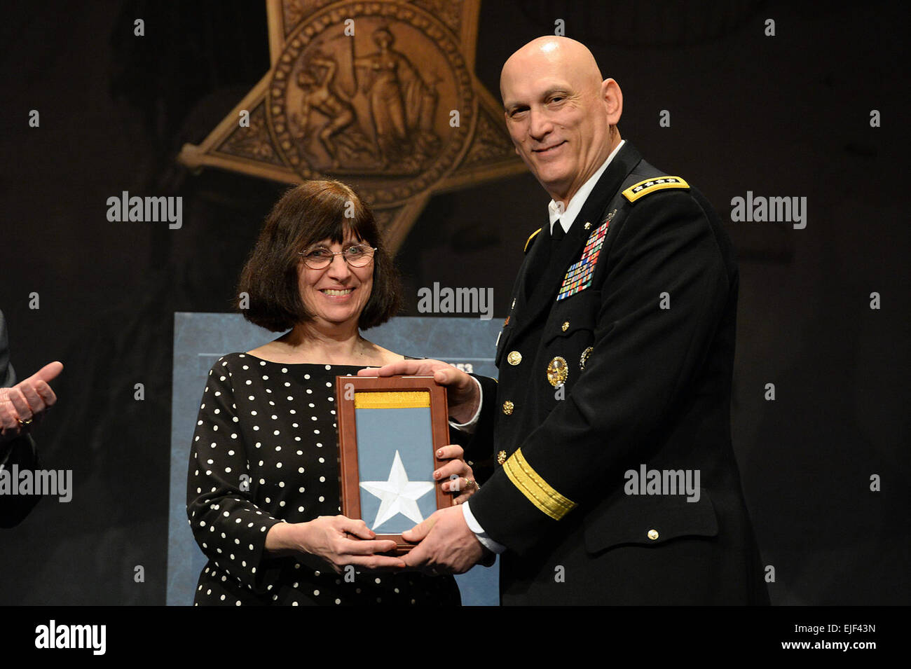 Chief of Staff of the Army, Gen. Raymond T. Odierno presents the Medal of Honor Flag to Patricia Kennedy, on behalf of her father, Pfc. William F. Leonard, one of 24 Army veterans to receive the flag during the Valor 24 Hall of Heroes Induction ceremony at the Pentagon, Washington D.C., March 19, 2014.  Mr. Leroy Council Stock Photo