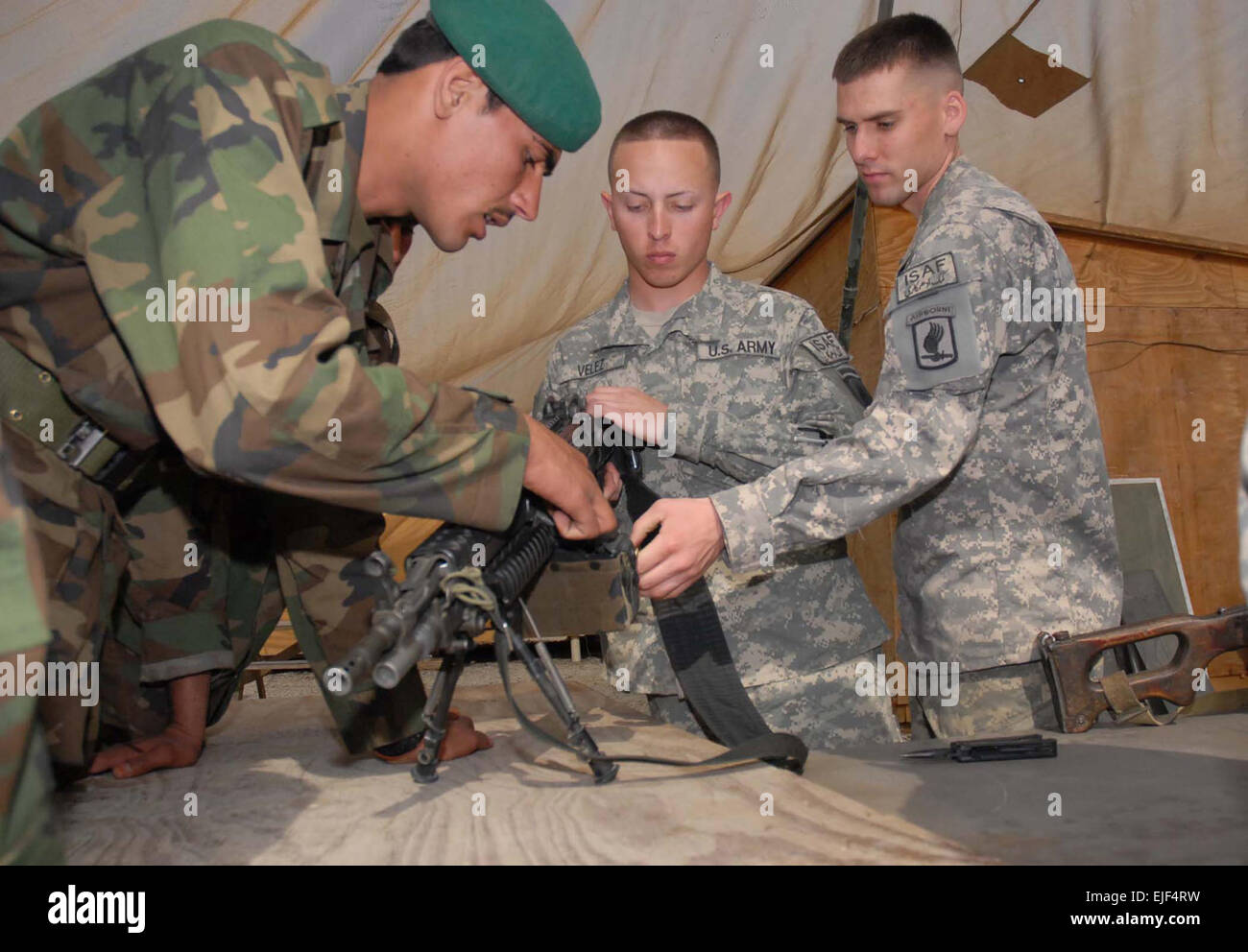 U.S. Army Spcs. Lee Gaskell, right, and Luis Velez-Casianoa, middle, both small-arms artillery repairmen in the armament shop of Bravo Company, 173rd Brigade Support Battalion, show Afghan National Army mechanics how to load an M-249 semi-automatic weapon during a weapons maintenance class on Forward Operating Base Fenty, Afghanistan, March 3, 2008.  2nd Lt. Monika Comeaux Released Stock Photo