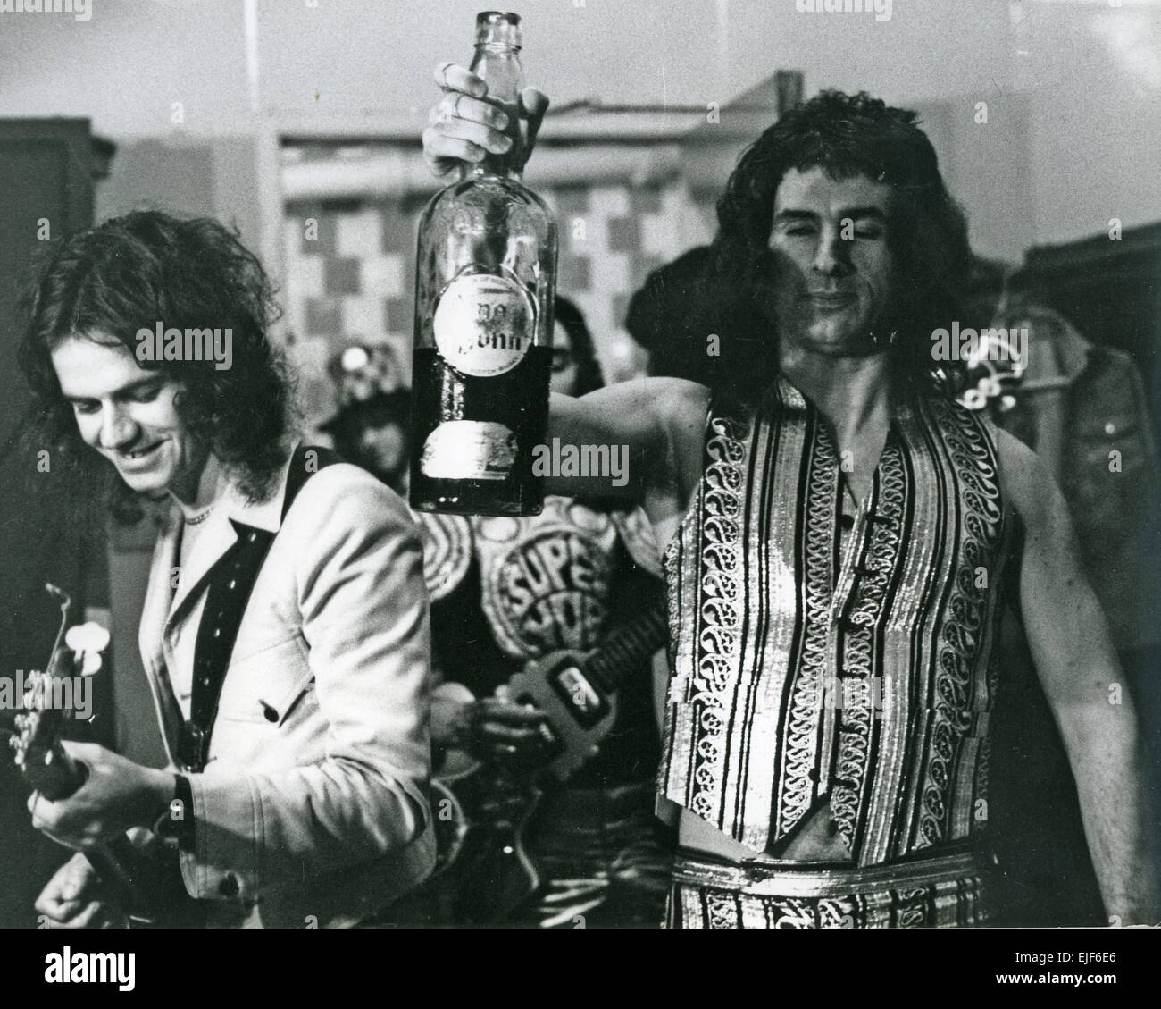 SLADE UK pop rock group in New York in 1973 with Jim Lea at left, Noddy Holder in background and Don Powell with the bottle Stock Photo