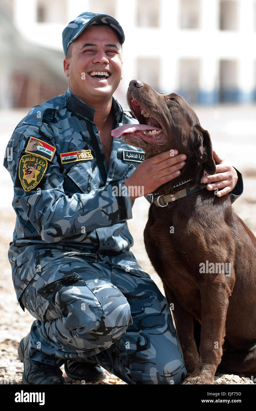 A dog handler with the Iraqi Police Al Anbar K-9 unit in Ramadi, Iraq, praises his dog, Sassy, a chocolate Labrador retriever, after she successfully found an explosive sample during training, April 16.         Anbar Police stand up K-9 unit  /-news/2010/04/23/37917-anbar-police-stand-up-k-9-unit/index.html Stock Photo
