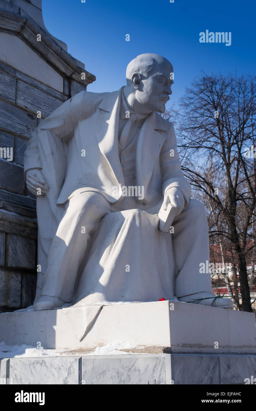 A statue of Lenin sitting down with a book and flowers Stock Photo