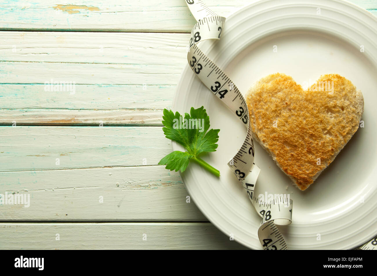 Heart shape toast on a plate with celery leaf and measuring tape Stock Photo