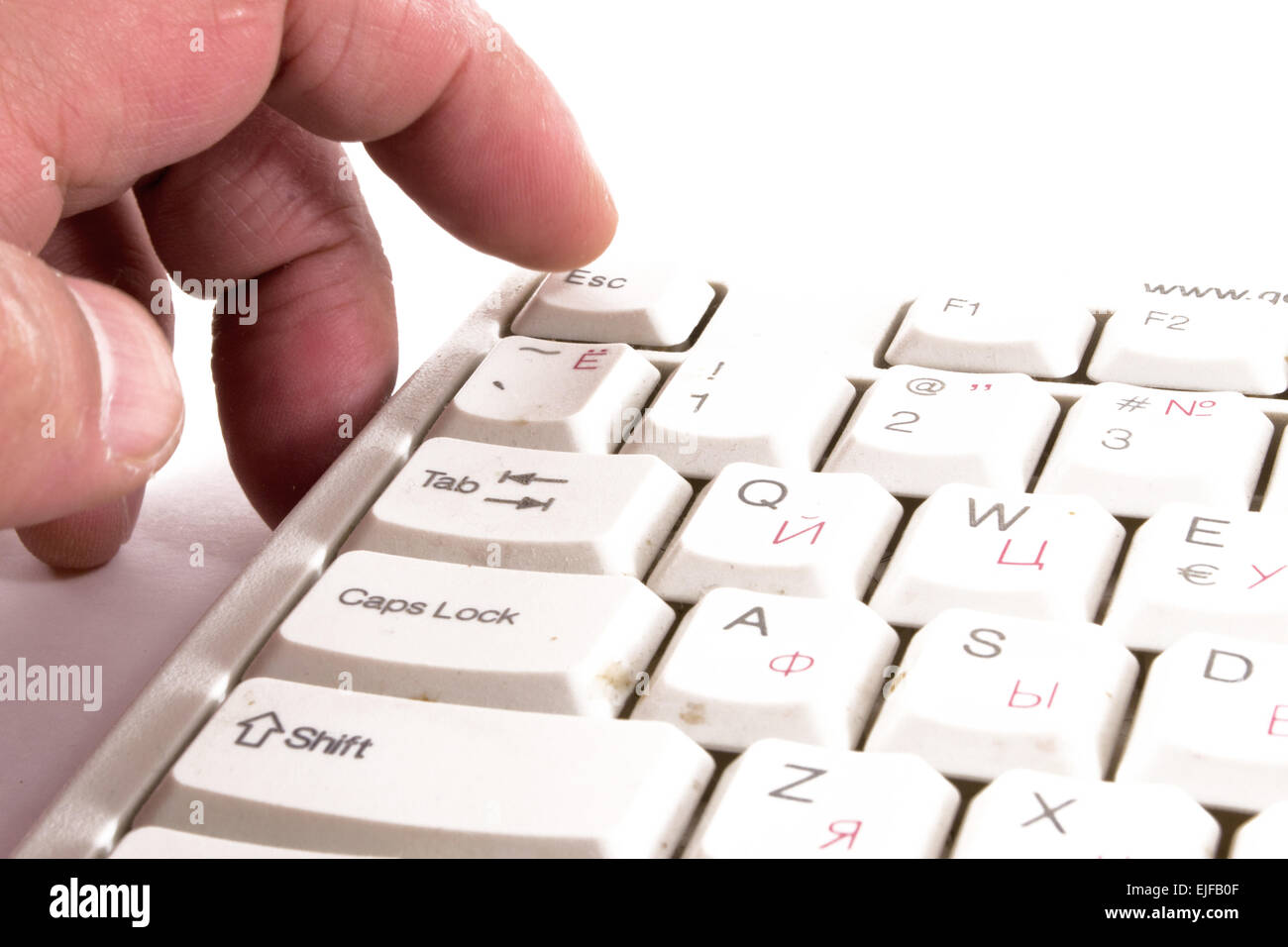 A male finger reaches to touch and press the escape key on a keyboard Stock Photo