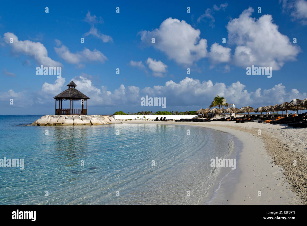 Clear warm water, blue sky, and a beach-side gazebo. Stock Photo