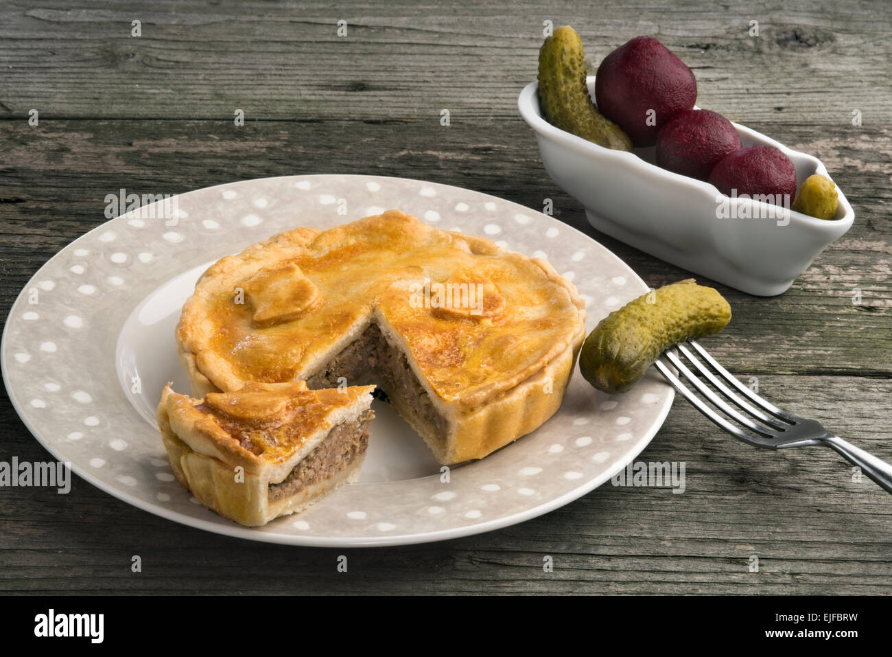 Traditional British pork pie with lard crust, gherkins and pickled red beet. Stock Photo