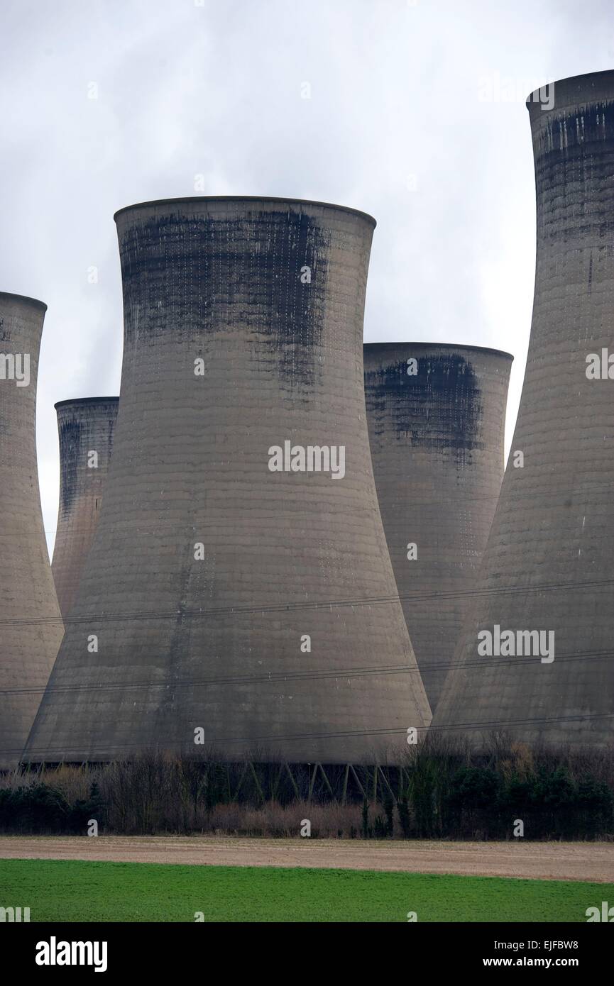Cooling towers and electricity pylons against a bright cloudy sky at