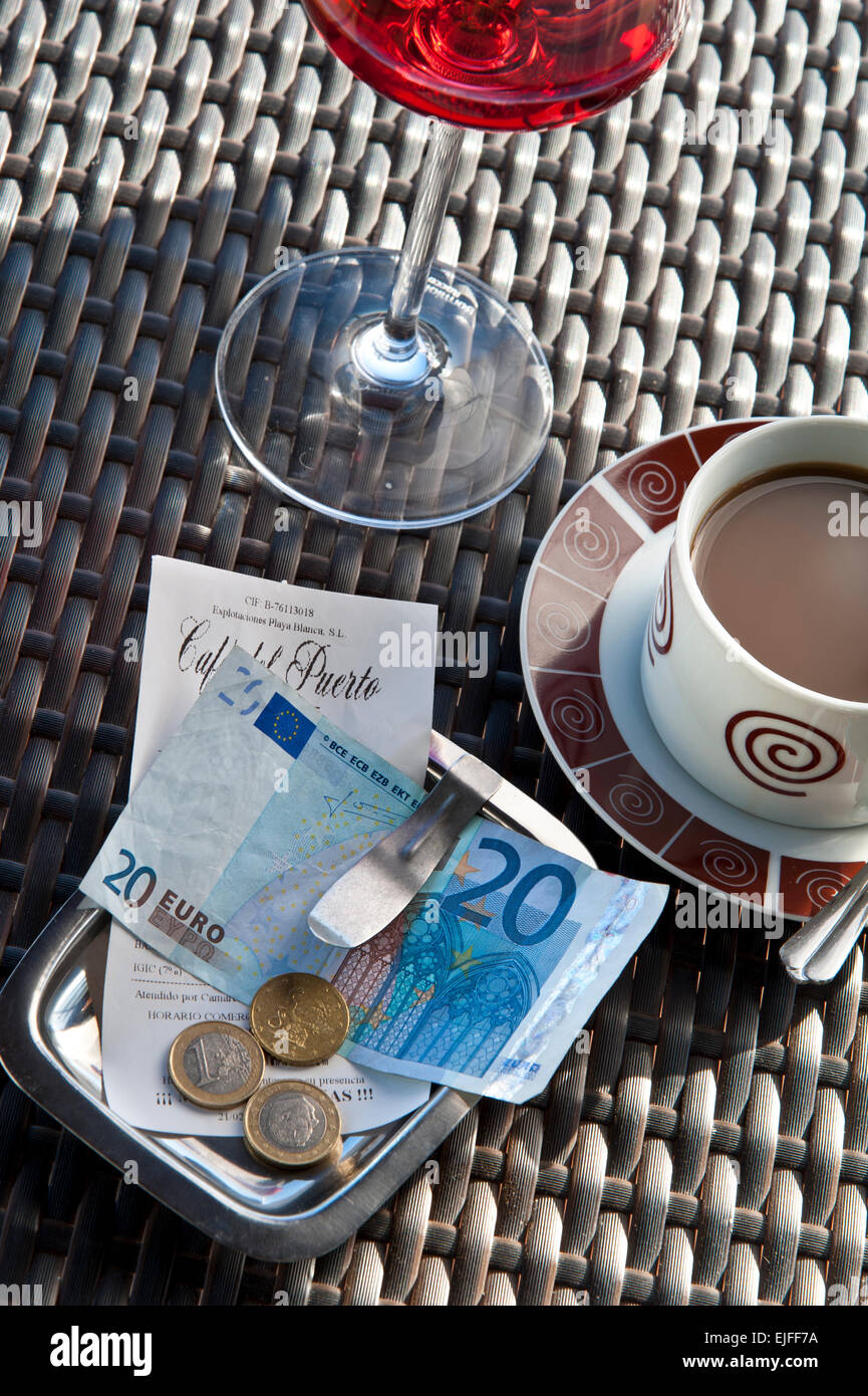 Bill with payment in Euros on sunny Spanish restaurant table with glass of rose wine and cup of coffee Stock Photo