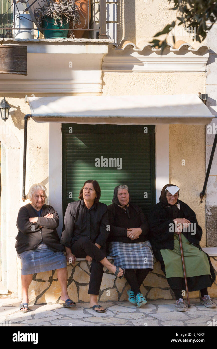 Elderly Corfiot women wearing traditional black clothes sitting relaxing in village square of Krini, Corfu, , Greece Stock Photo