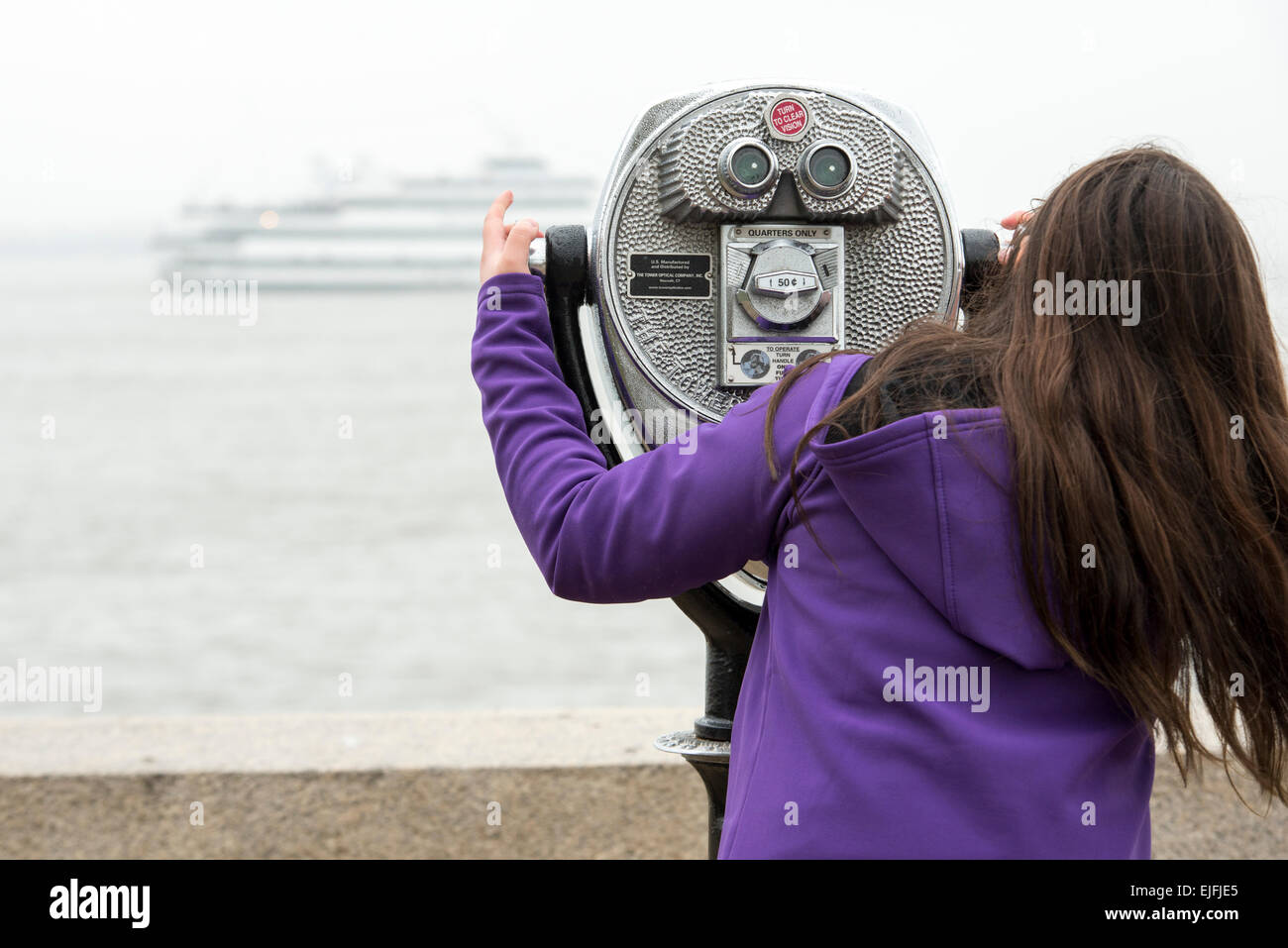 Woman using binoculars at Upper New York Bay, Ellis Island, Jersey City, New York State, USA Stock Photo