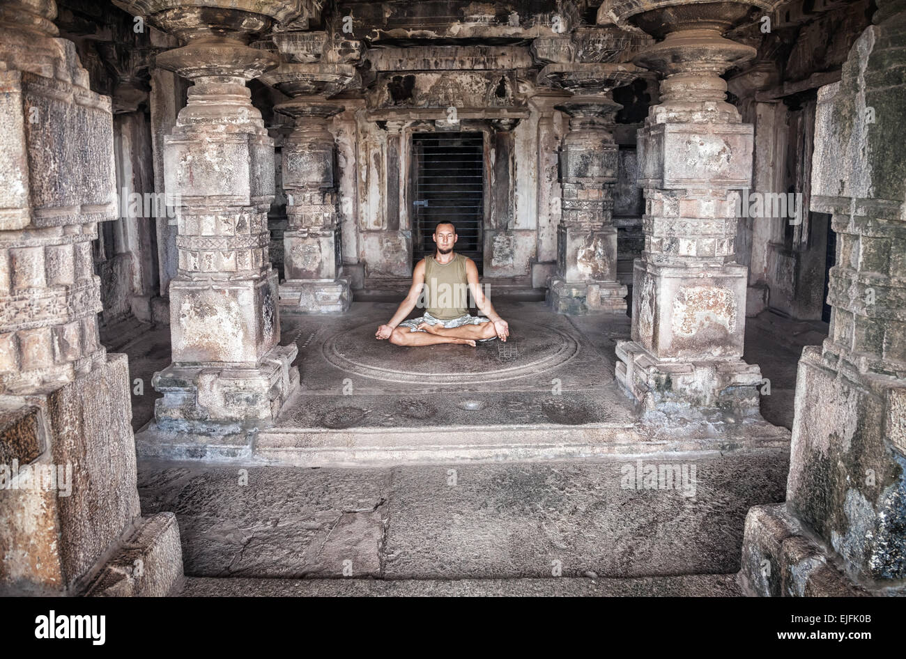 Man doing meditation in ancient temple with carving columns in Hampi, Karnataka, India Stock Photo