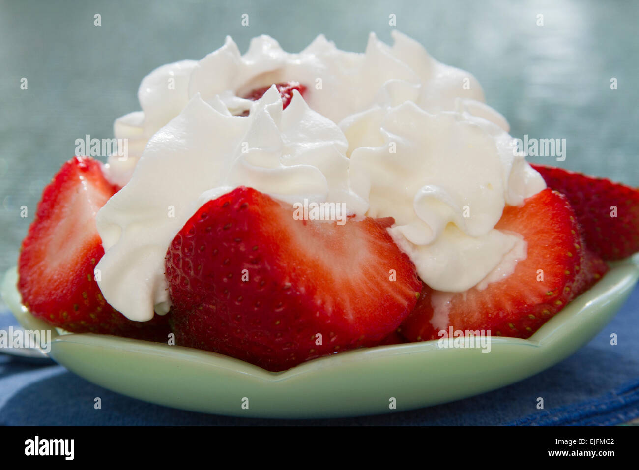 Sliced Strawberries With Whipped Cream On A Decorative Green Plate