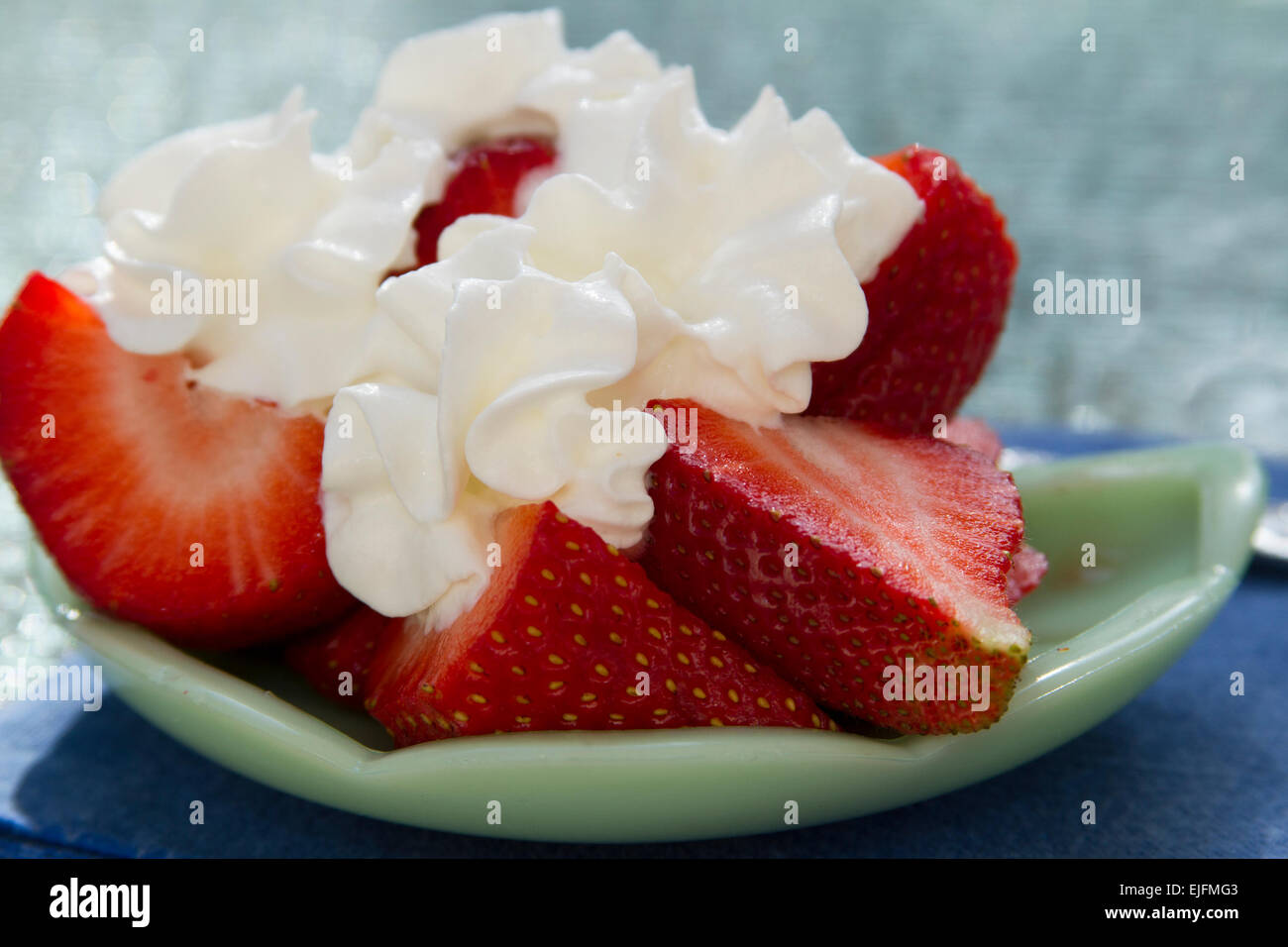 Sliced Strawberries With Whipped Cream On A Decorative Green Plate
