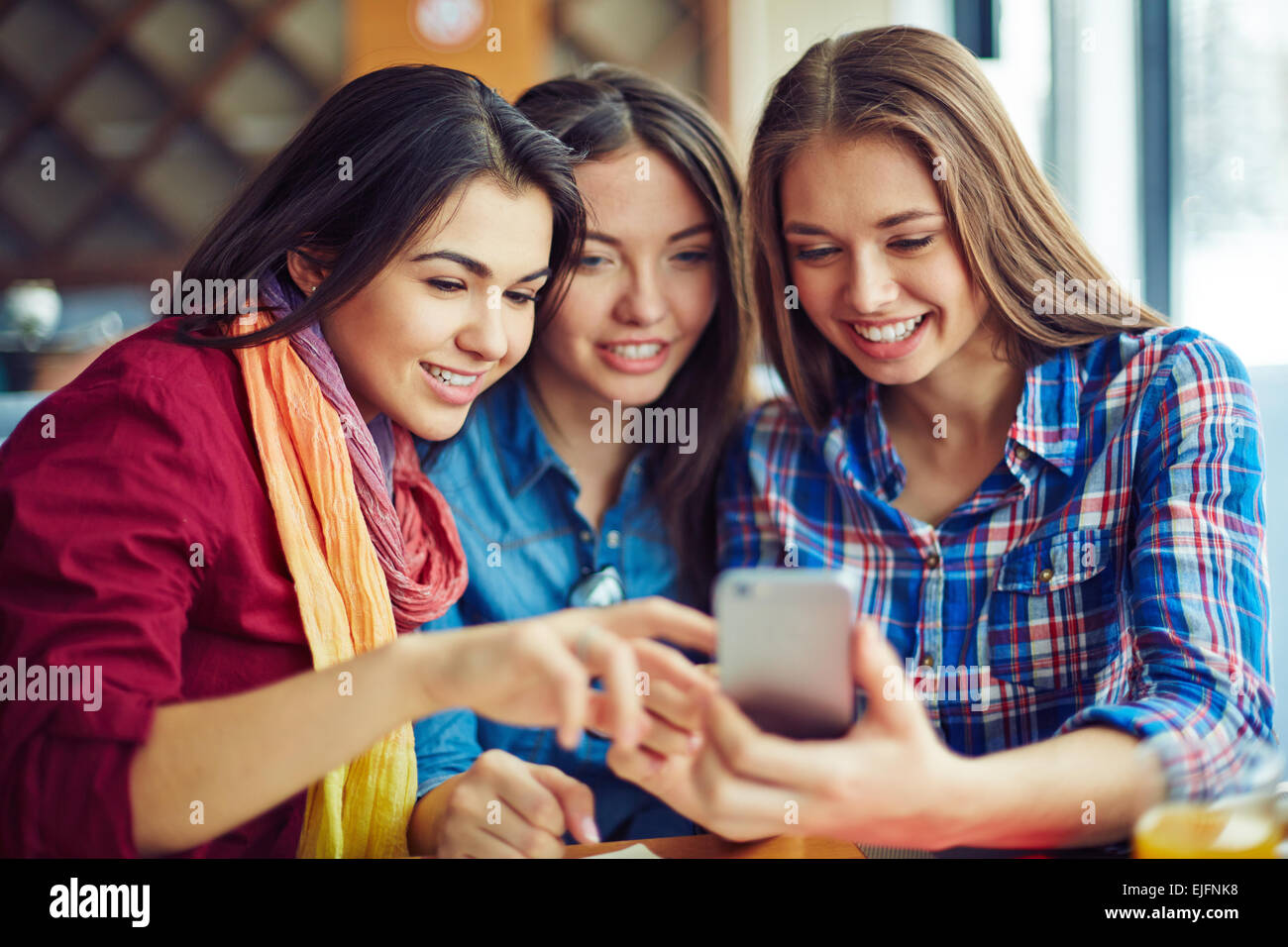 Smiling girls looking through photos in telephone Stock Photo