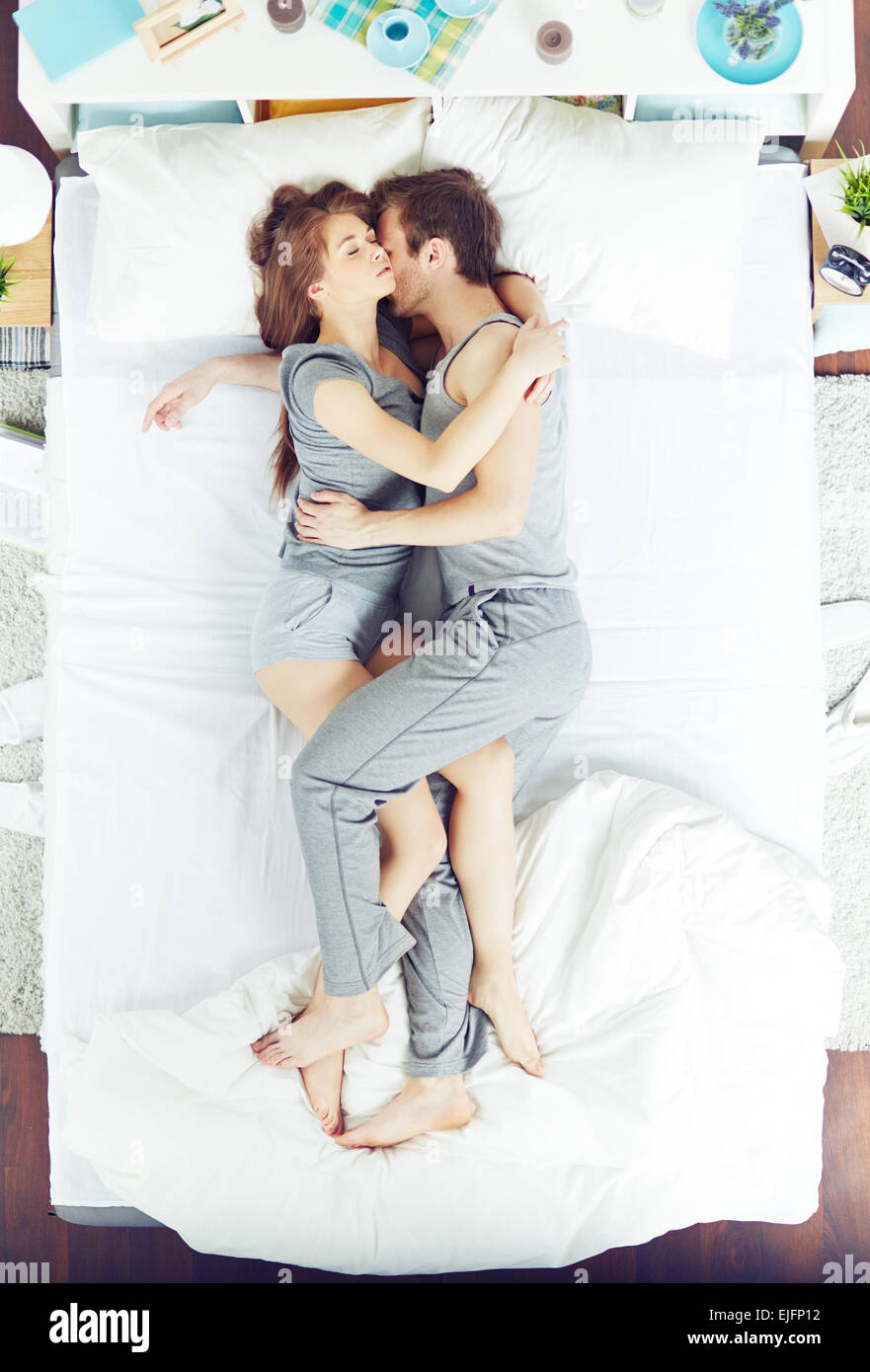 Young couple sleeping in bed in embrace Stock Photo