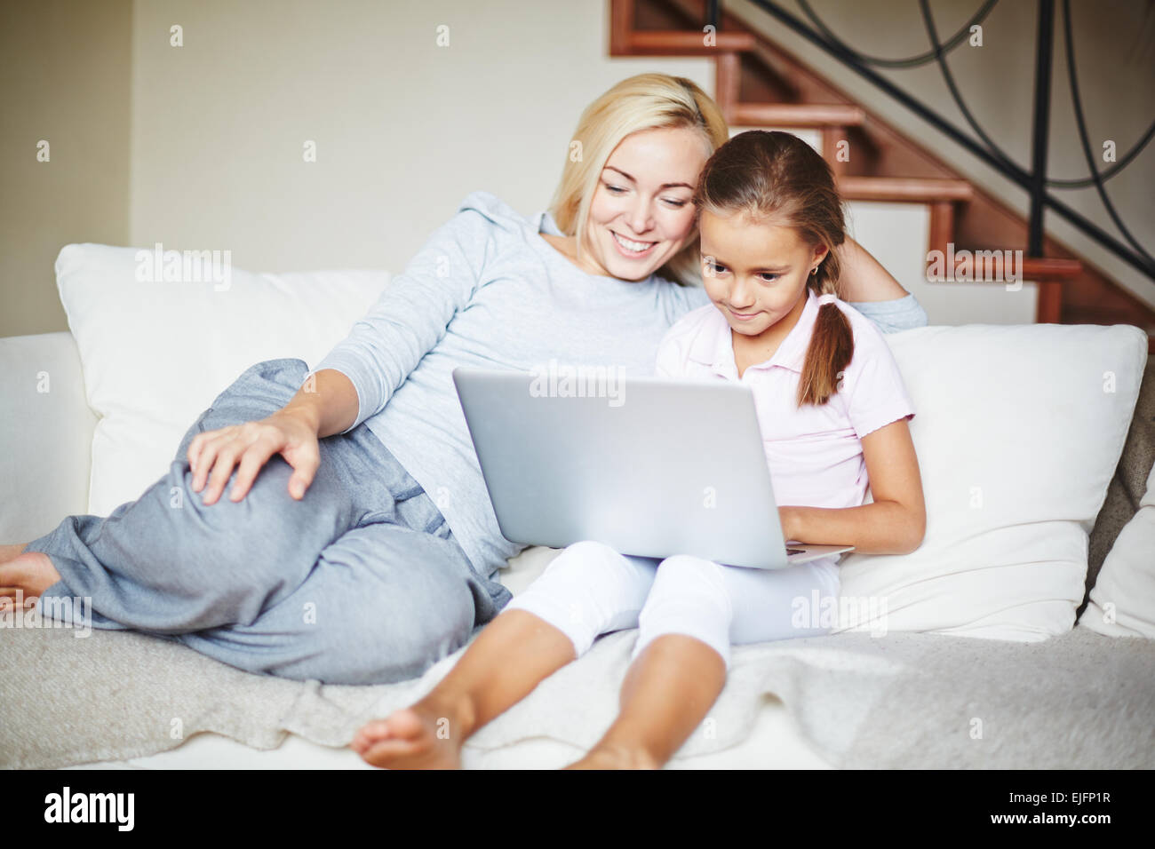Smiling mother and daughter using laptop at home Stock Photo