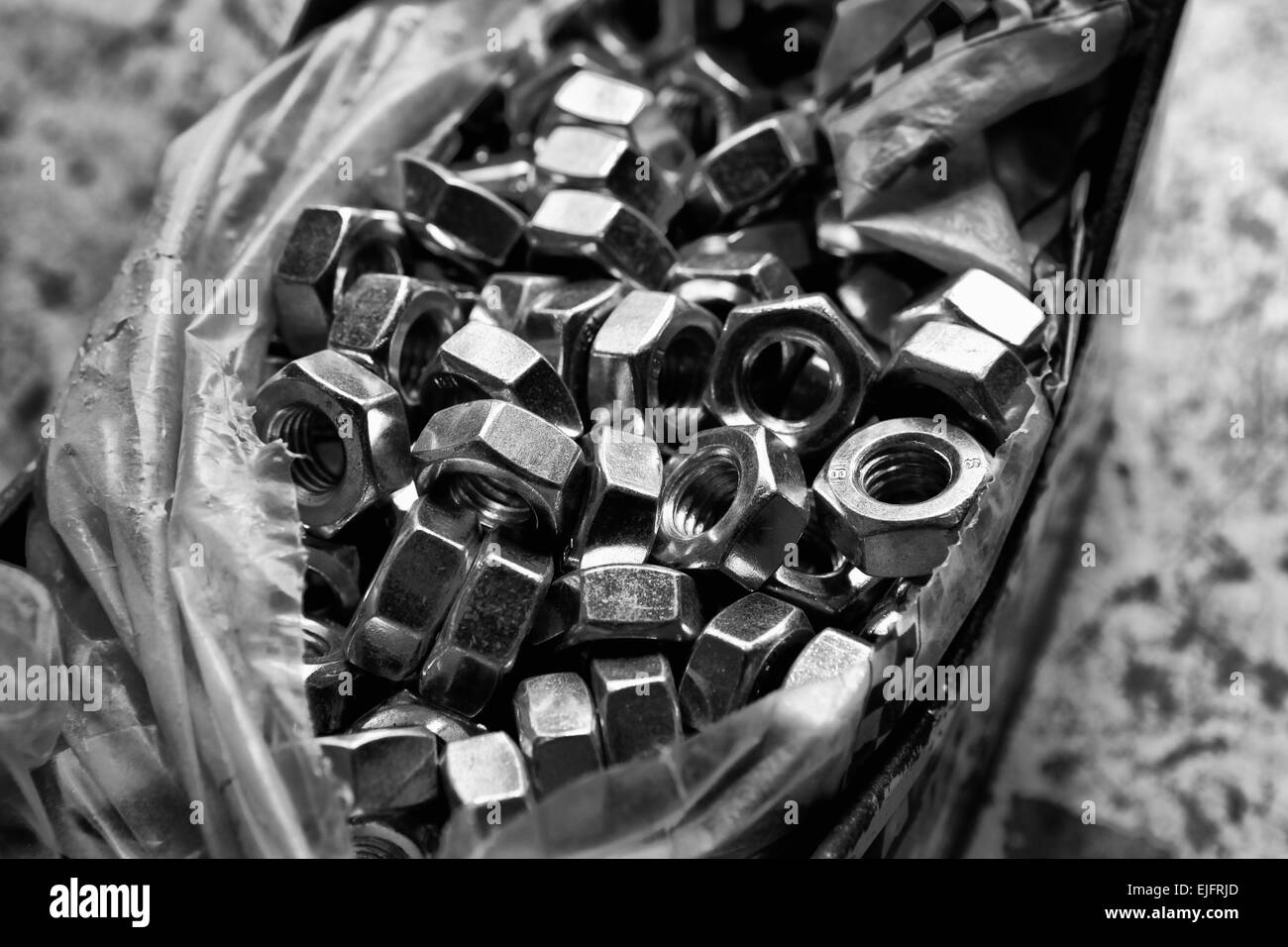 Plastic bag of load of new alloy nuts over a mechanic table Stock Photo