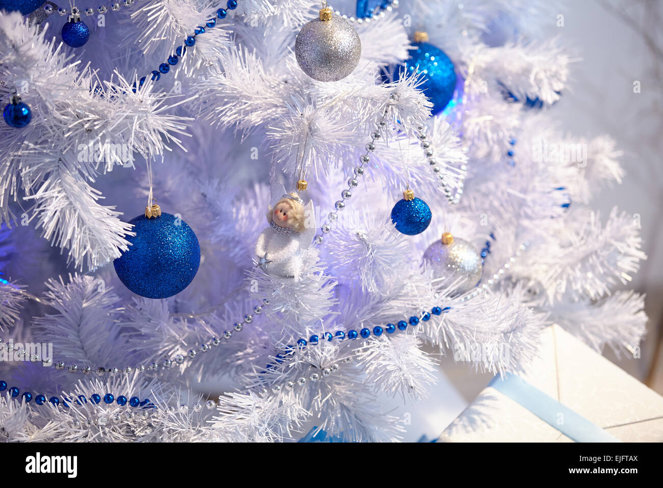 White Christmas tree with a blue toy, garlands, beads Stock Photo - Alamy