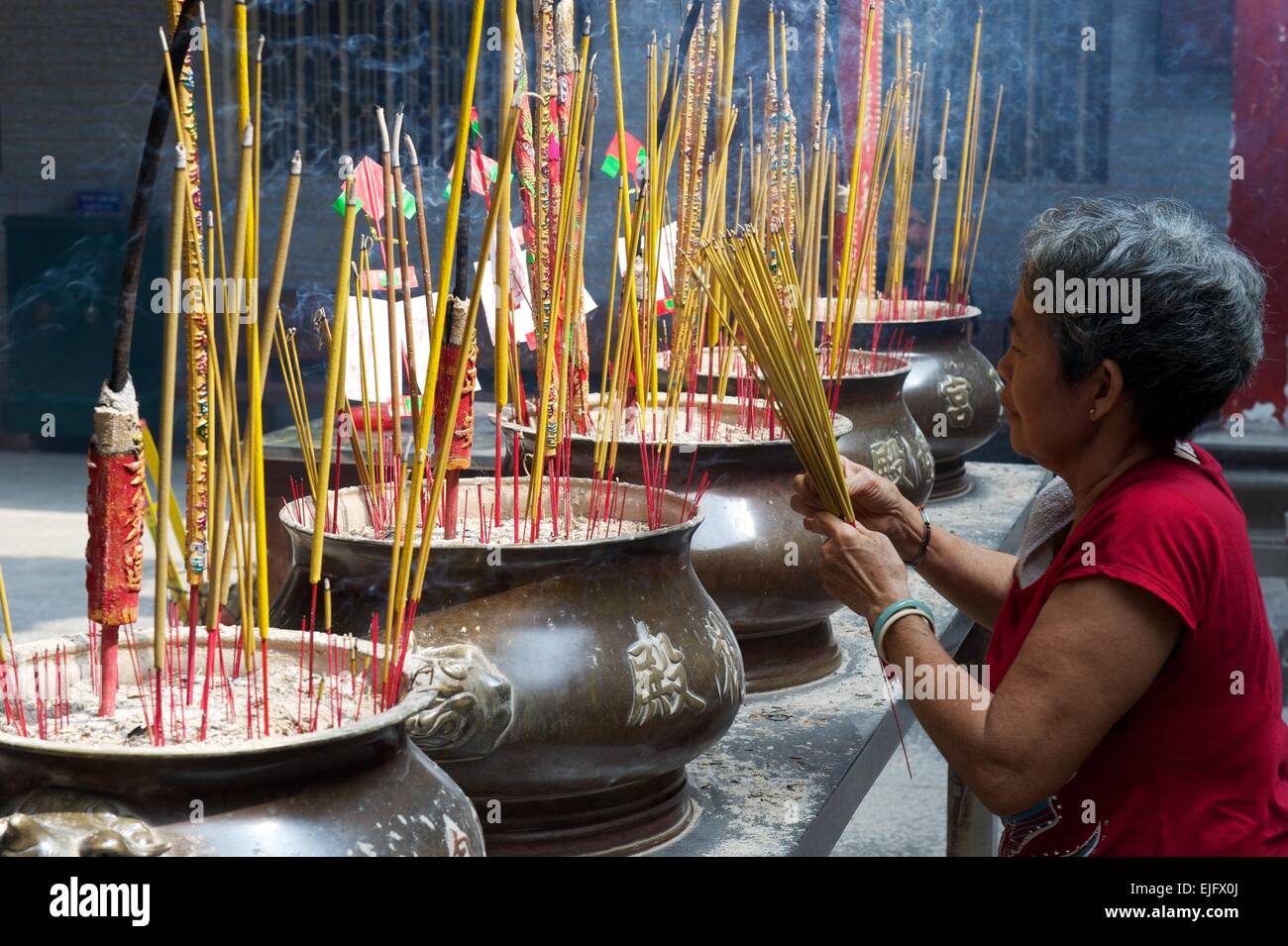 Woman lighting incense sticks, Chinese Temple, Ho Chi Minh City, Vietnam Stock Photo