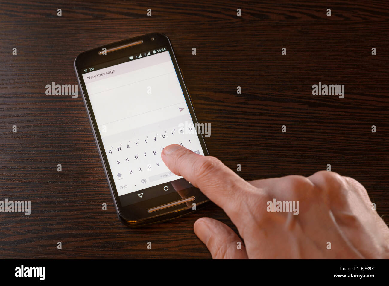 A man is typing an sms on the keypad of his black smartphone Stock Photo