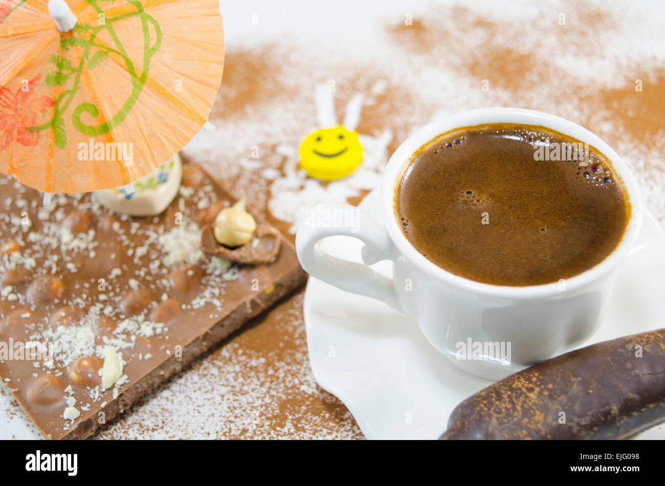 Cup of coffee with a subtly heart shaped foam decorated with flowers and banana shaped chocolate Stock Photo