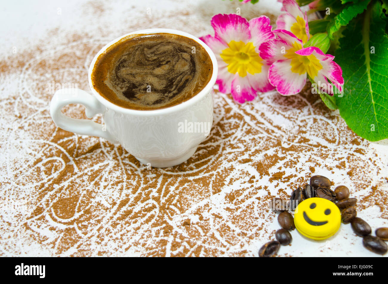 Cup of coffee with a subtly heart shaped foam decorated with flowers and banana shaped chocolate Stock Photo