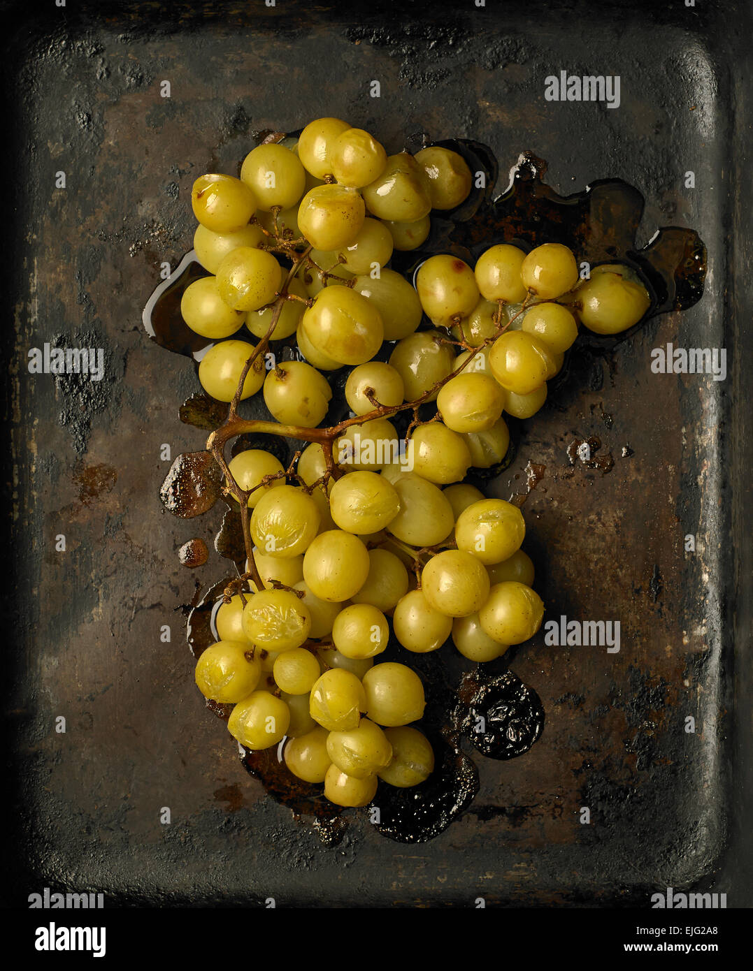 An overhead image of a bunch of roasted green grapes in a roasting tray Stock Photo
