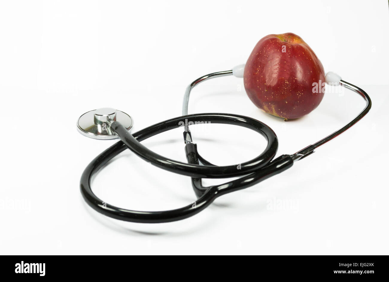 Red apple held between the ears of a medical stethoscope , conceptual