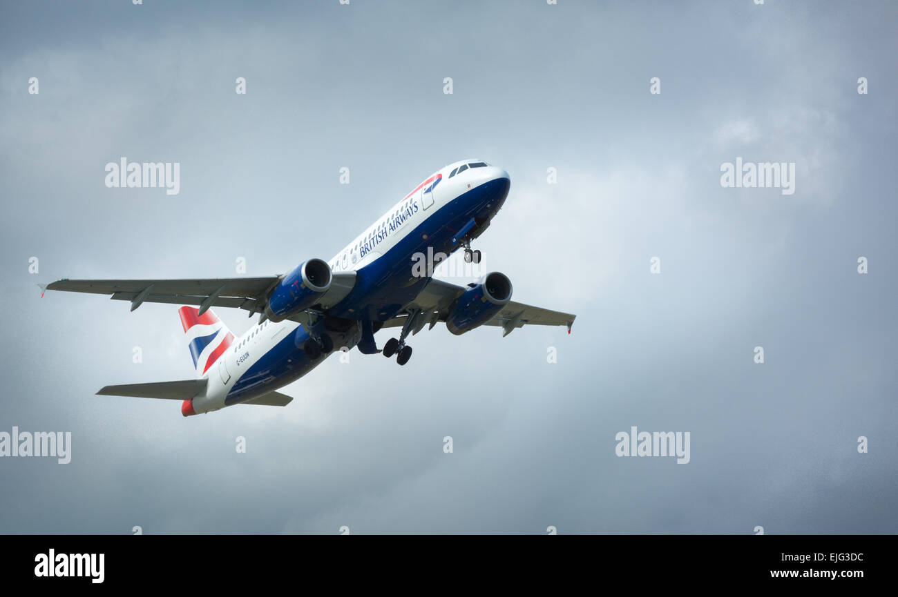 British Airways plane in flight in bright light against cloudy sky Stock Photo