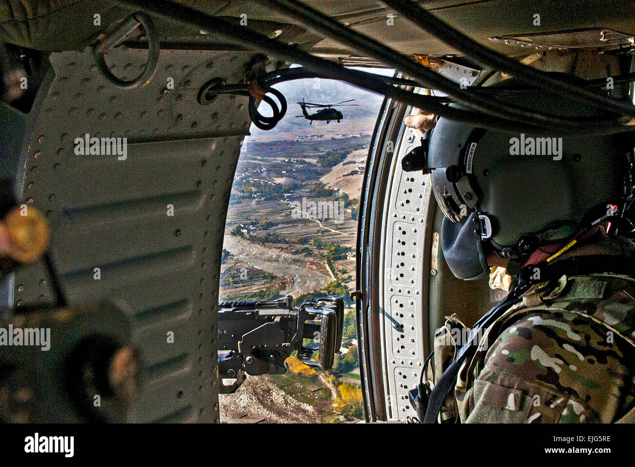 U.S. Army Capt. Tim Beecher with the 82nd Combat Aviation Brigade, Task Force Talon, mans his weapon on the door of a UH-60 Black Hawk as it and another Black Hawk fly near the Tora Bora area along the Pakistan border Nov. 5 Stock Photo