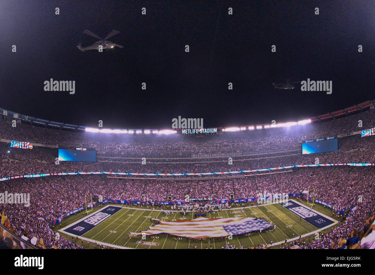 EAST RUTHERFORD, N.J. - Blackhawk helicopters from the New Jersey Air National Guard perform a flyover while Soldiers, Marines, sailors, Coast Guardsmen,  and airmen display a U.S.-shaped American flag across the field during  pre-game ceremonies for the NFL's season opening game between the New York Giants and Dallas Cowboys at MetLife Stadium, Sept. 5. More than 60 service members presented the large flag as Queen Latifah sang the national anthem. US Army  John Manley Stock Photo