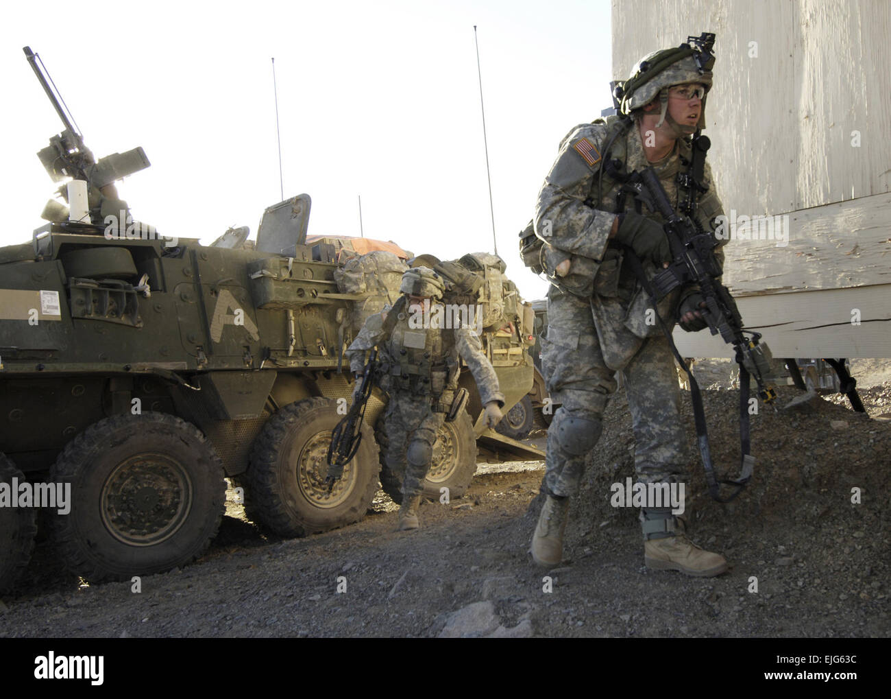 U.S. Army Soldiers charge around a building during a training exercise ...